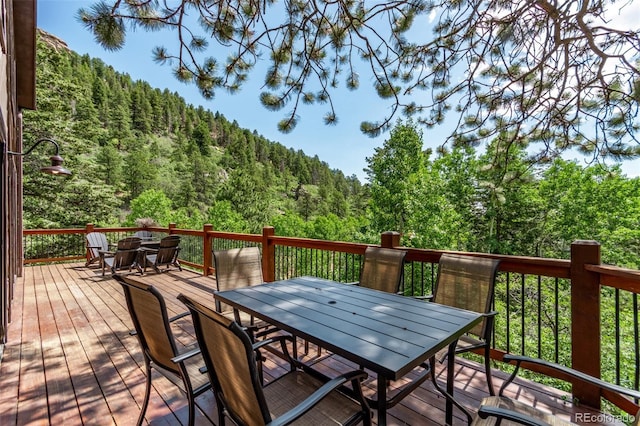 20223 Goins Dr, Morrison, CO 80465 - wooden deck with outdoor dining space and a view of trees