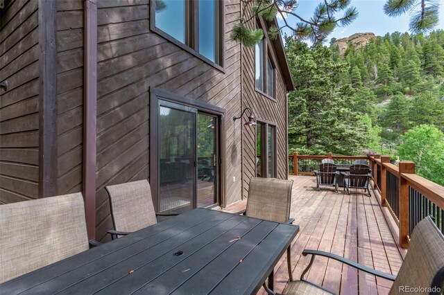 20223 Goins Dr, Morrison, CO 80465 - wooden deck with outdoor dining area and a view of trees