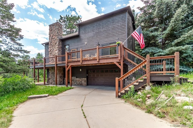 20223 Goins Dr, Morrison, CO 80465 - rear view of house with a garage, a wooden deck, driveway, a chimney, and stone siding