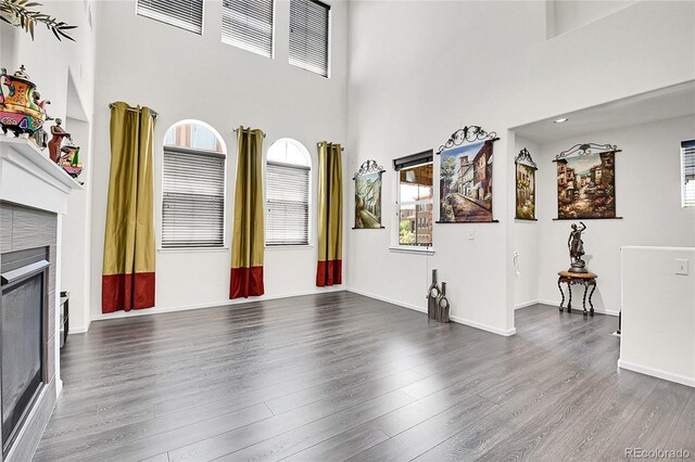 3437 Rosato Dr Unit C, Highlands Ranch, CO 80126 - unfurnished living room with a tiled fireplace, wood finished floors, a high ceiling, and baseboards