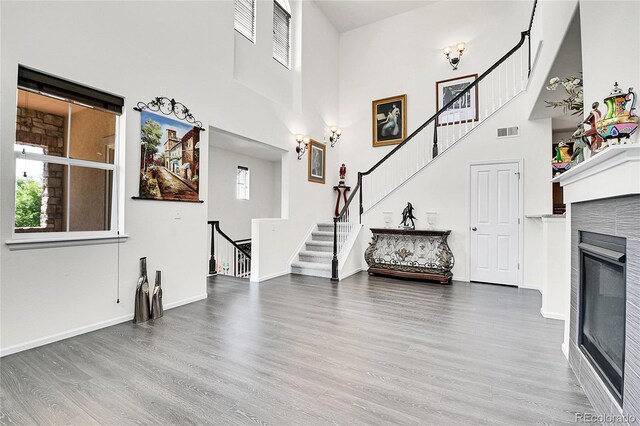 3437 Rosato Dr Unit C, Highlands Ranch, CO 80126 - unfurnished living room featuring wood finished floors, a high ceiling, stairway, a glass covered fireplace, and baseboards