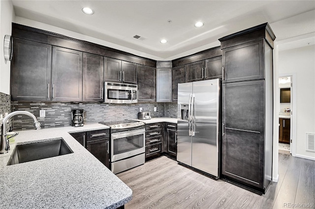 3437 Rosato Dr Unit C, Highlands Ranch, CO 80126 - kitchen with stainless steel appliances, a sink, light wood-style floors, light stone countertops, and decorative backsplash