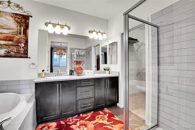 3437 Rosato Dr Unit C, Highlands Ranch, CO 80126 - full bathroom with a shower stall, a walk in closet, double vanity, a garden tub, and a chandelier