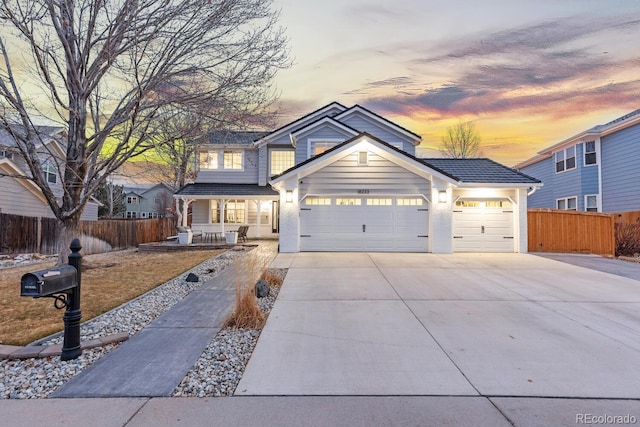 traditional home with a tiled roof, driveway, a garage, and fence