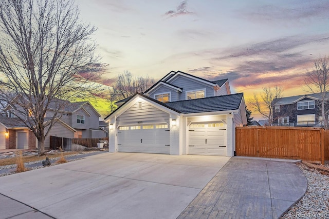 view of front of property featuring concrete driveway, fence, and a tile roof