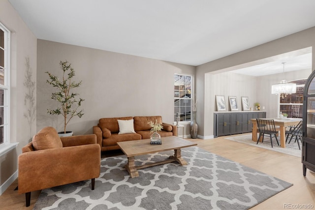 living area with a chandelier, light wood-type flooring, and baseboards