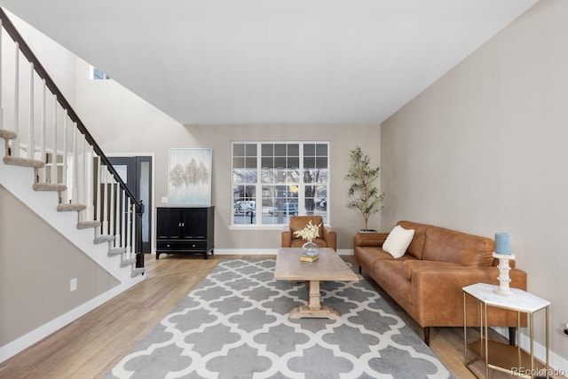 living area with stairway, baseboards, and wood finished floors