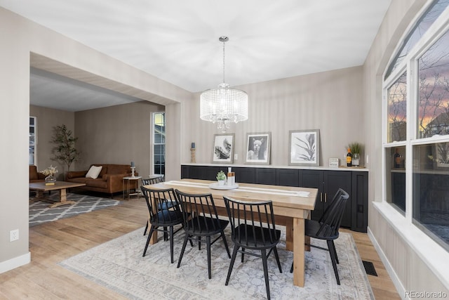 dining area with a chandelier, visible vents, light wood-type flooring, and baseboards