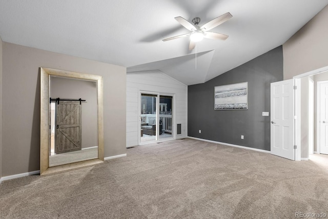 unfurnished bedroom featuring a barn door, baseboards, carpet flooring, and vaulted ceiling