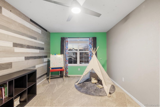 recreation room with an accent wall, wooden walls, baseboards, and carpet floors