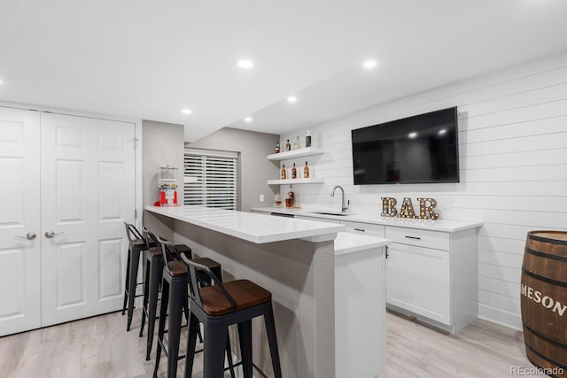 bar featuring wet bar, recessed lighting, a sink, decorative backsplash, and light wood-type flooring