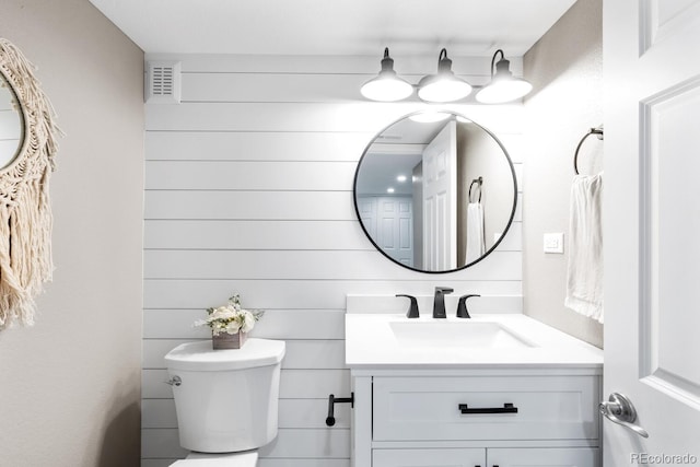 half bathroom with visible vents, toilet, and vanity