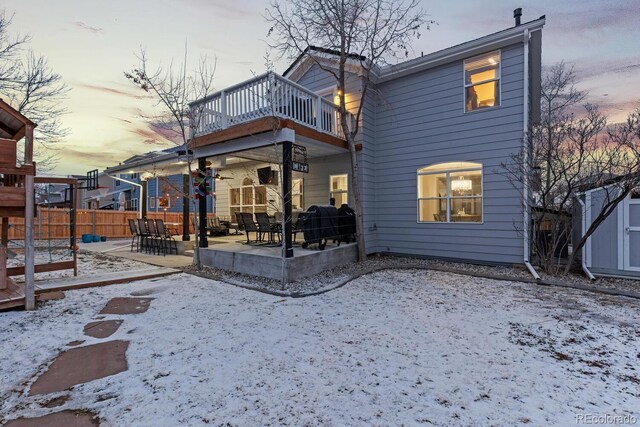 snow covered back of property with a patio, a balcony, and fence