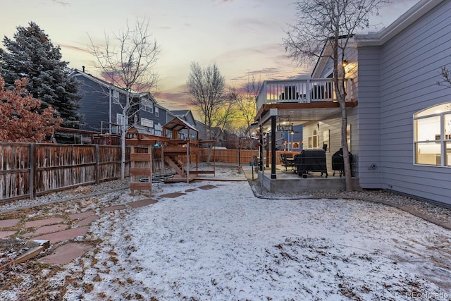 snowy yard featuring a patio area and a fenced backyard