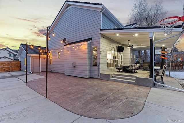 back of property at dusk featuring a gate, ceiling fan, a patio, and fence