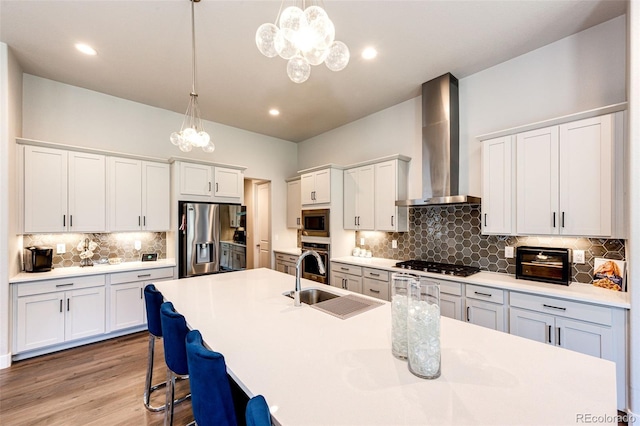 kitchen featuring wall chimney exhaust hood, sink, appliances with stainless steel finishes, and decorative light fixtures