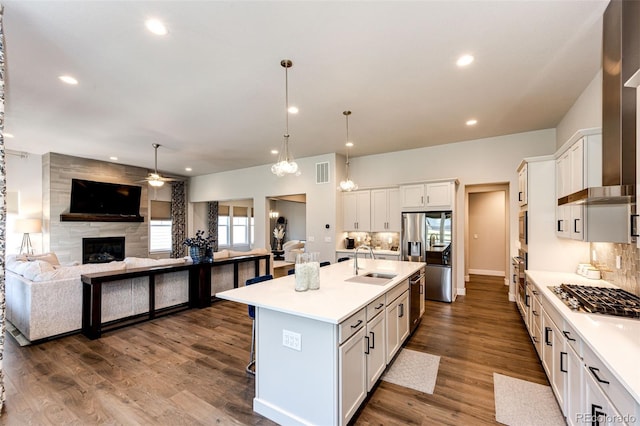 kitchen with white cabinets, dark hardwood / wood-style flooring, appliances with stainless steel finishes, an island with sink, and sink