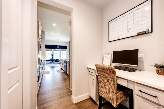 home office featuring built in desk, light hardwood / wood-style floors, and sink