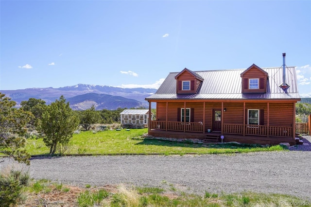 cabin with a front yard, a mountain view, and covered porch