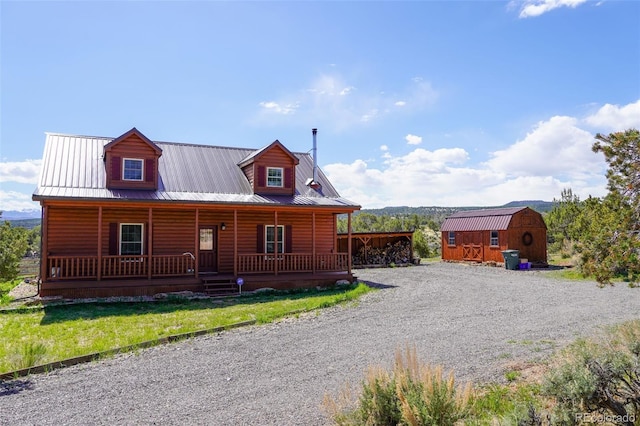 log-style house with a porch and a storage shed