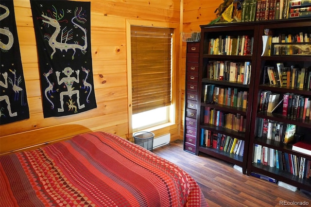 bedroom featuring hardwood / wood-style flooring, a baseboard radiator, and wooden walls