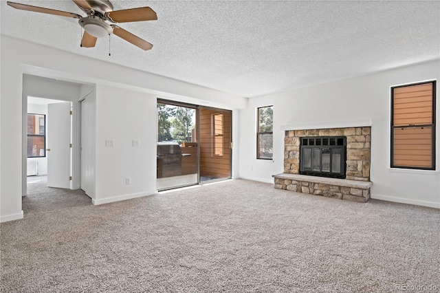 unfurnished living room featuring carpet, ceiling fan, a stone fireplace, and a textured ceiling