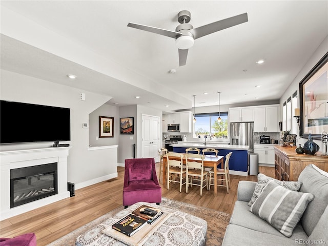 6162 W 28th Ct, Edgewater, CO 80214 - living room featuring ceiling fan, light wood-type flooring, recessed lighting, a glass covered fireplace, and baseboards