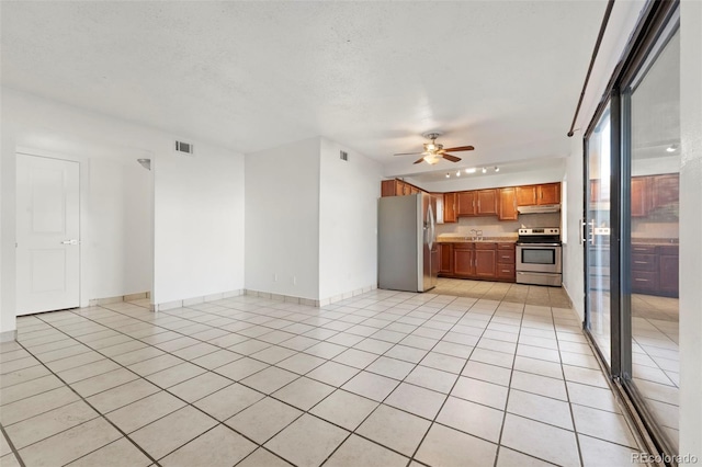 unfurnished living room featuring a textured ceiling, ceiling fan, light tile patterned floors, and sink