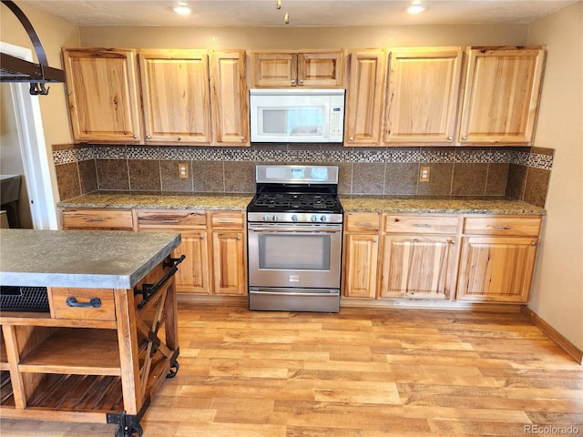 kitchen with gas stove, light hardwood / wood-style floors, and backsplash