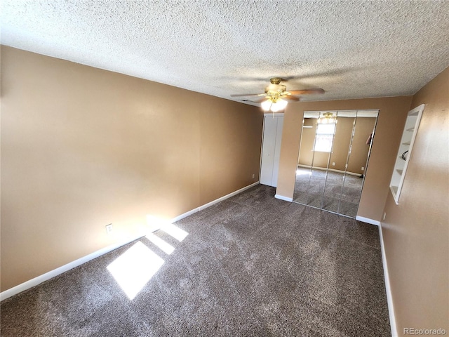 unfurnished room featuring dark carpet, ceiling fan, and a textured ceiling