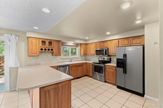 kitchen with sink, stainless steel appliances, a textured ceiling, light tile patterned flooring, and kitchen peninsula