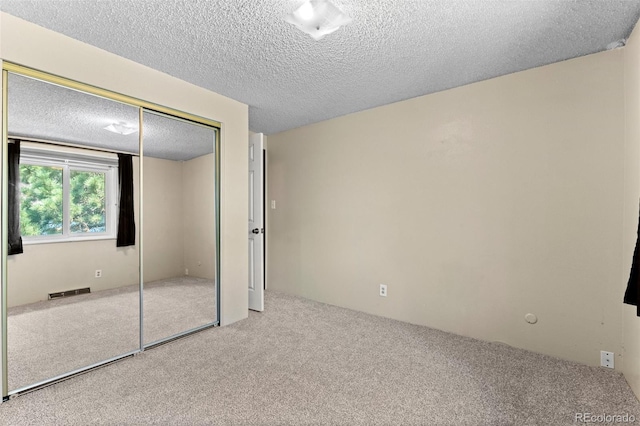 unfurnished bedroom featuring carpet floors, a closet, and a textured ceiling