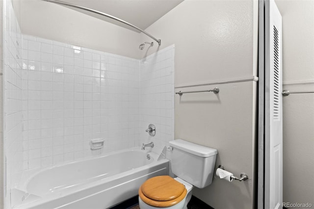 bathroom featuring tiled shower / bath combo and toilet