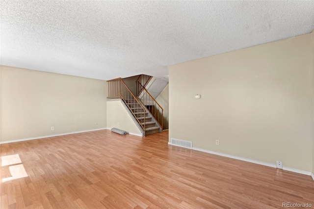 unfurnished living room featuring light hardwood / wood-style flooring and a textured ceiling