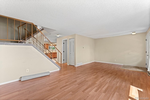 unfurnished living room with hardwood / wood-style flooring and a textured ceiling