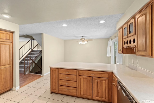 kitchen with light tile patterned floors, dishwasher, ceiling fan, a textured ceiling, and kitchen peninsula