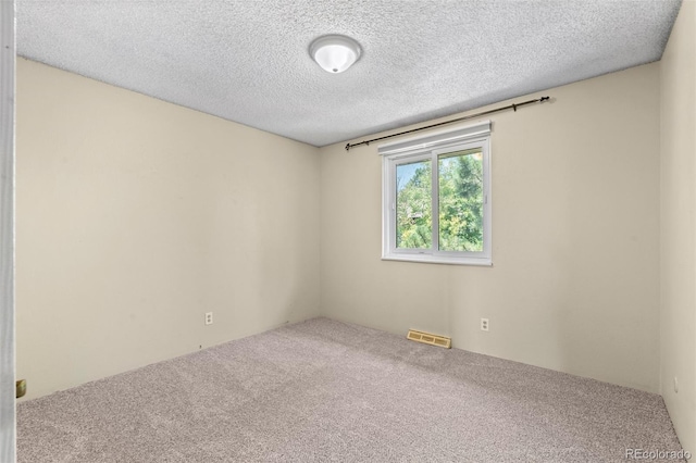 carpeted spare room with a textured ceiling