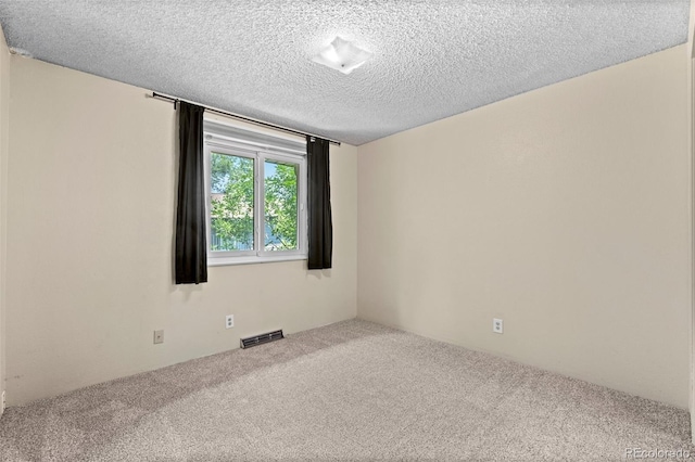 empty room with carpet flooring and a textured ceiling