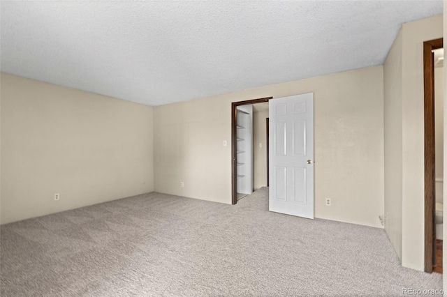 spare room with light carpet and a textured ceiling