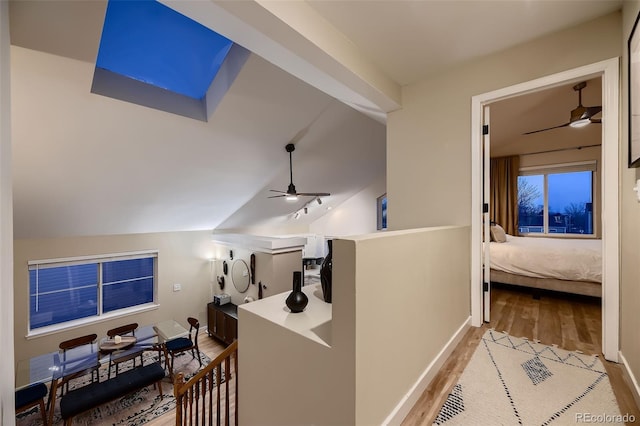 corridor with vaulted ceiling and light hardwood / wood-style flooring