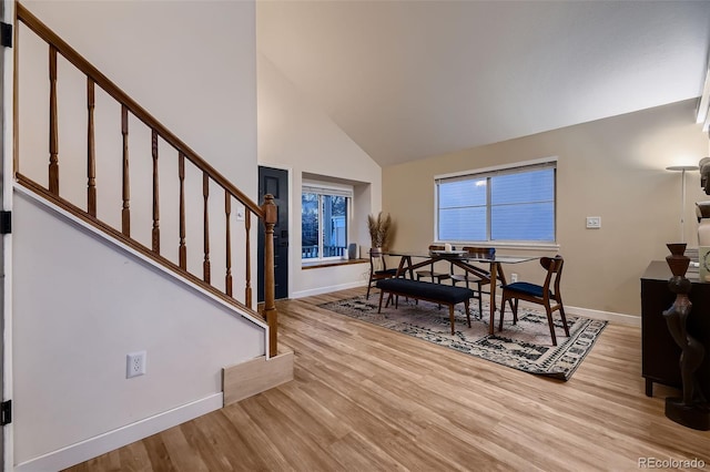 dining space with high vaulted ceiling and light wood-type flooring