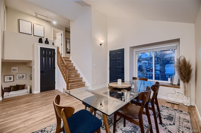 dining area with high vaulted ceiling and light wood-type flooring