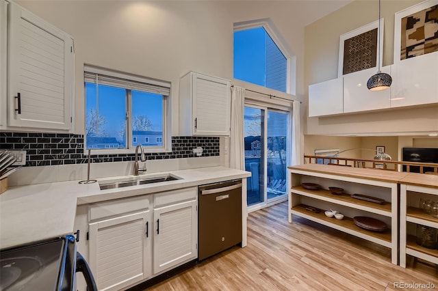 kitchen featuring sink, white cabinetry, stainless steel dishwasher, decorative backsplash, and range