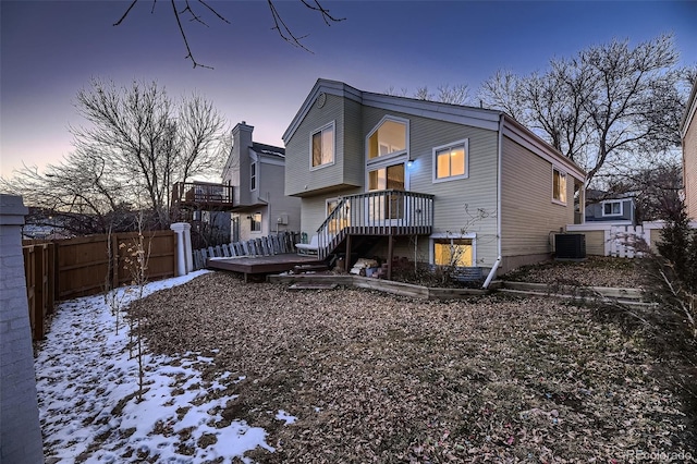 snow covered property with central AC unit and a wooden deck