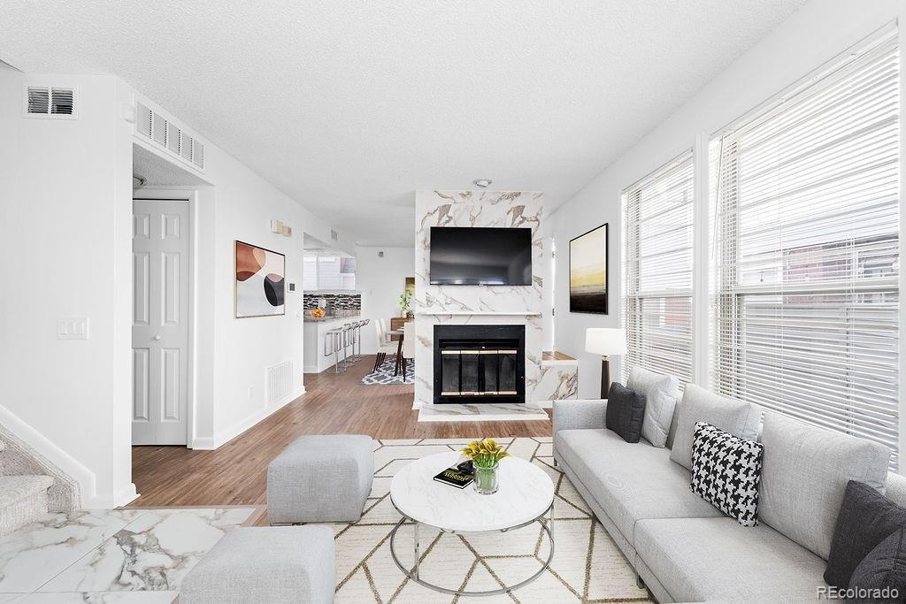 living room featuring a high end fireplace, wood-type flooring, and a textured ceiling