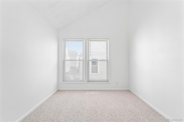 carpeted spare room with vaulted ceiling and a textured ceiling