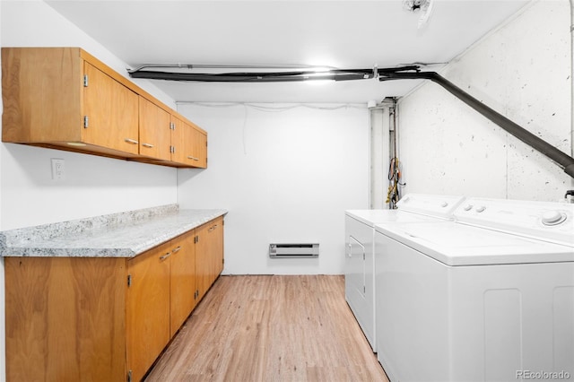 laundry area with cabinets, a baseboard radiator, washer and clothes dryer, and light wood-type flooring