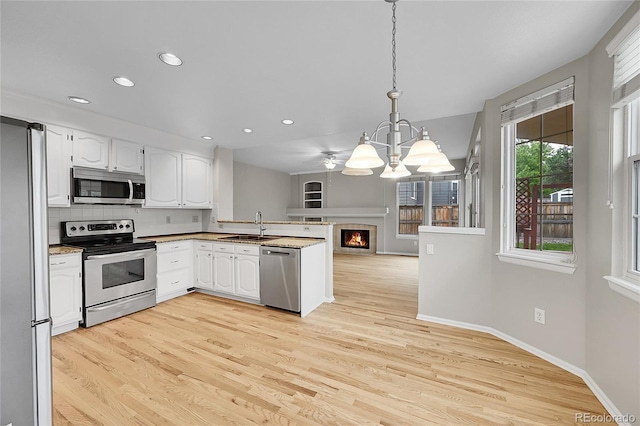 2316 Weatherstone Cir, Highlands Ranch, CO 80126 - kitchen with appliances with stainless steel finishes, a peninsula, white cabinets, a chandelier, and recessed lighting
