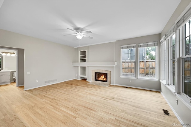 2316 Weatherstone Cir, Highlands Ranch, CO 80126 - unfurnished living room featuring light wood-style flooring, ceiling fan, built in shelves, and a tile fireplace