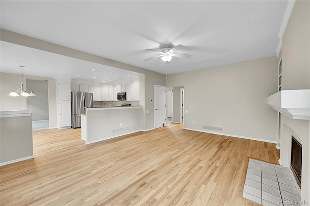 2316 Weatherstone Cir, Highlands Ranch, CO 80126 - unfurnished living room with light wood-style floors, ceiling fan, a fireplace with flush hearth, recessed lighting, and a chandelier